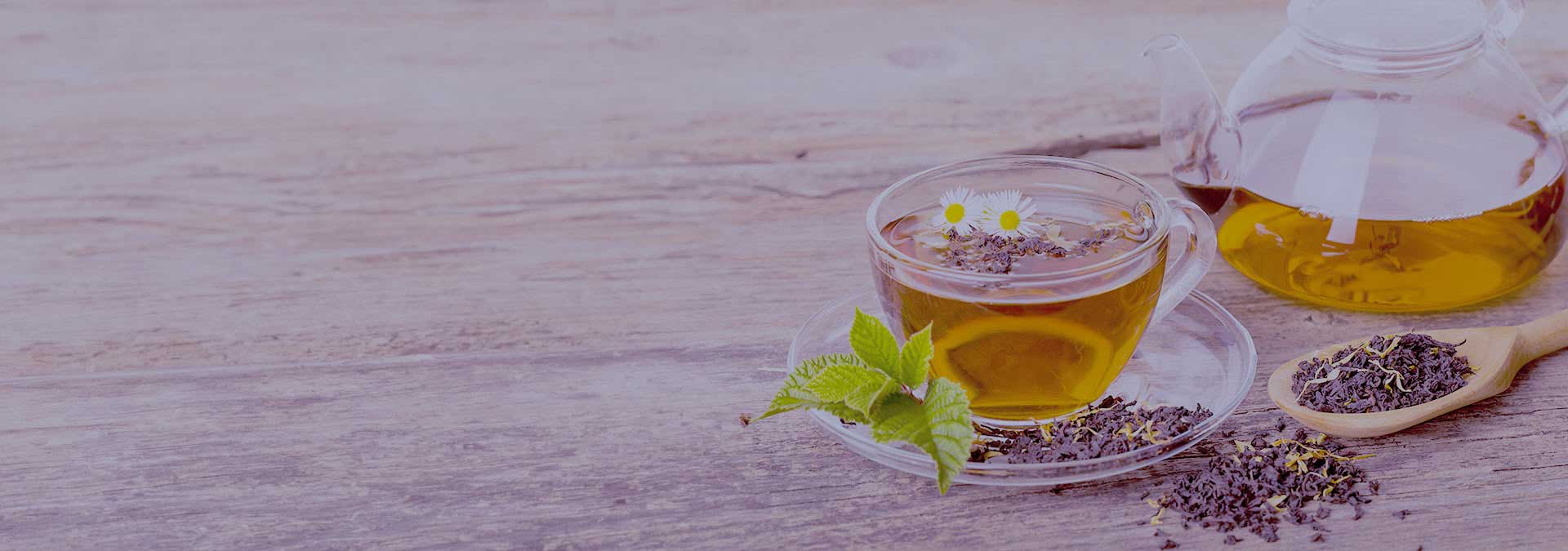 Gläserne Teekanne und gläserne Teetasse mit Kräutertee auf einem hölzernen Untergrund